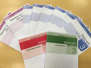 Nationella prov i svenska och matematik ligger upplagda på ett bord.