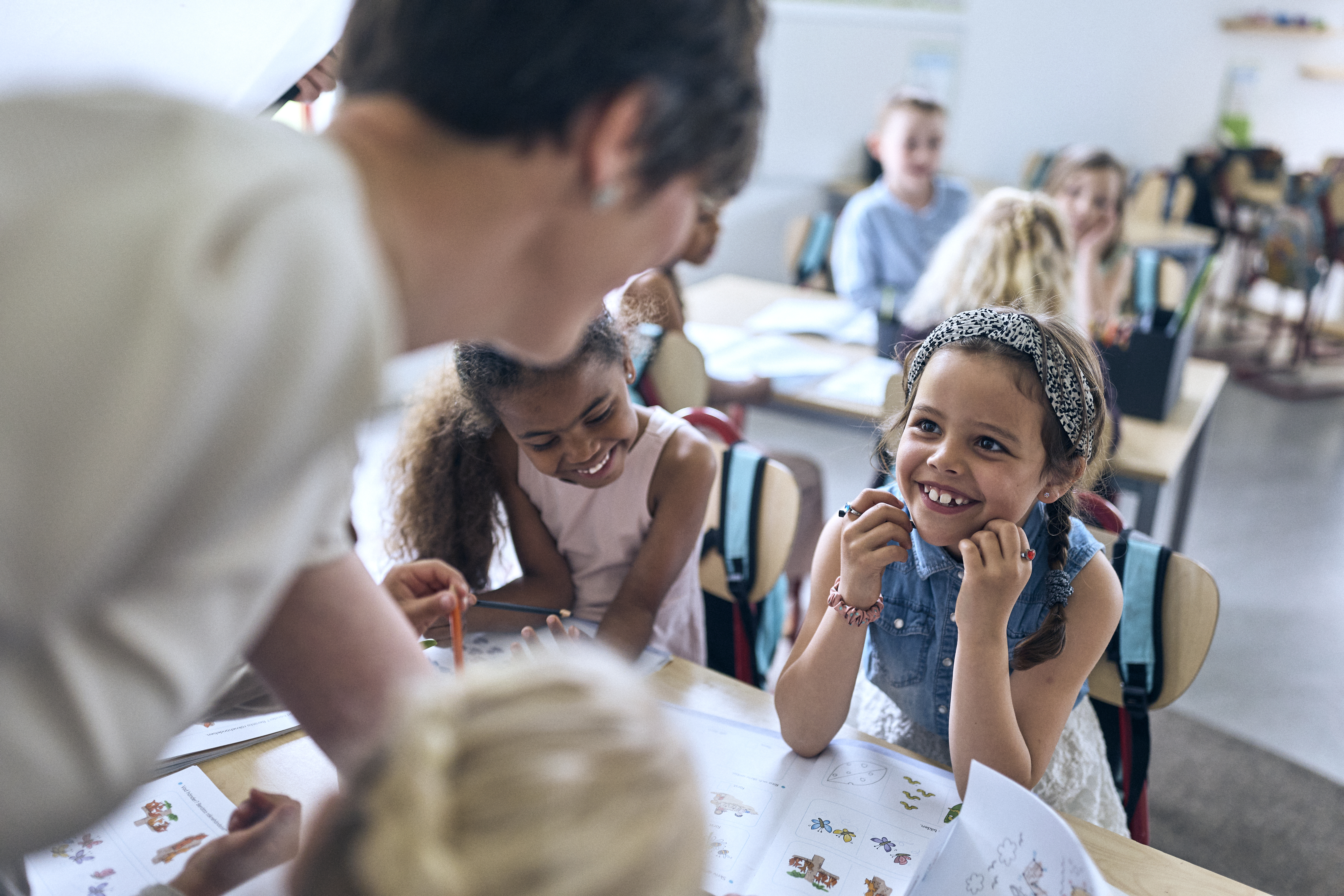 Lågstadieelev tittar upp på sin lärare och ler.
