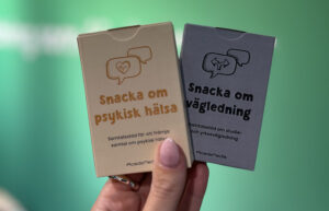 två kortlekar hålls av en hand mot grön bakgrund