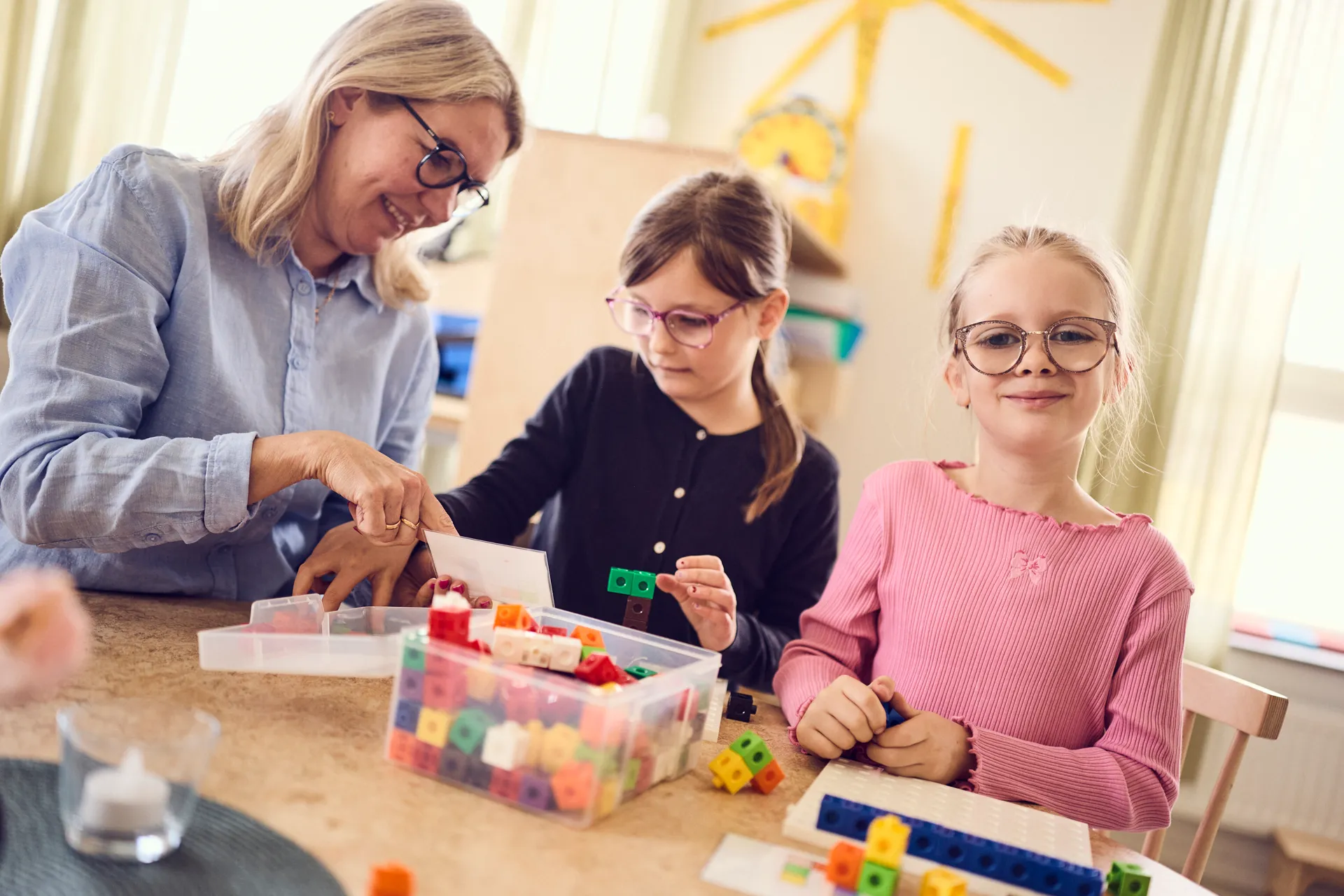 En kvinna och två flickor leker med klossar.