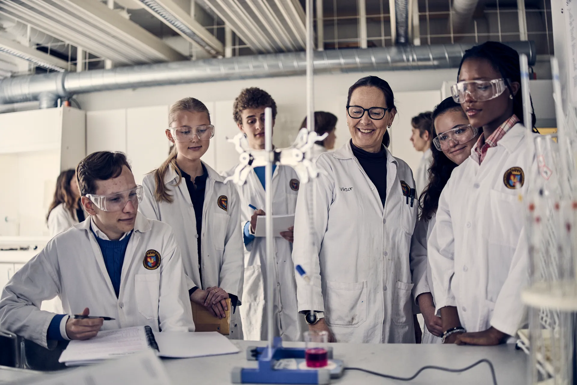 En grupp människor i labbrockar som står runt ett bord.